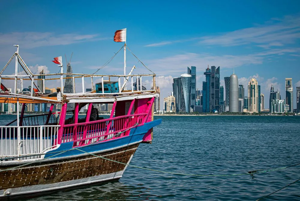 A tour boat moored on the Doha Corniche with the West Bay skyline behind it