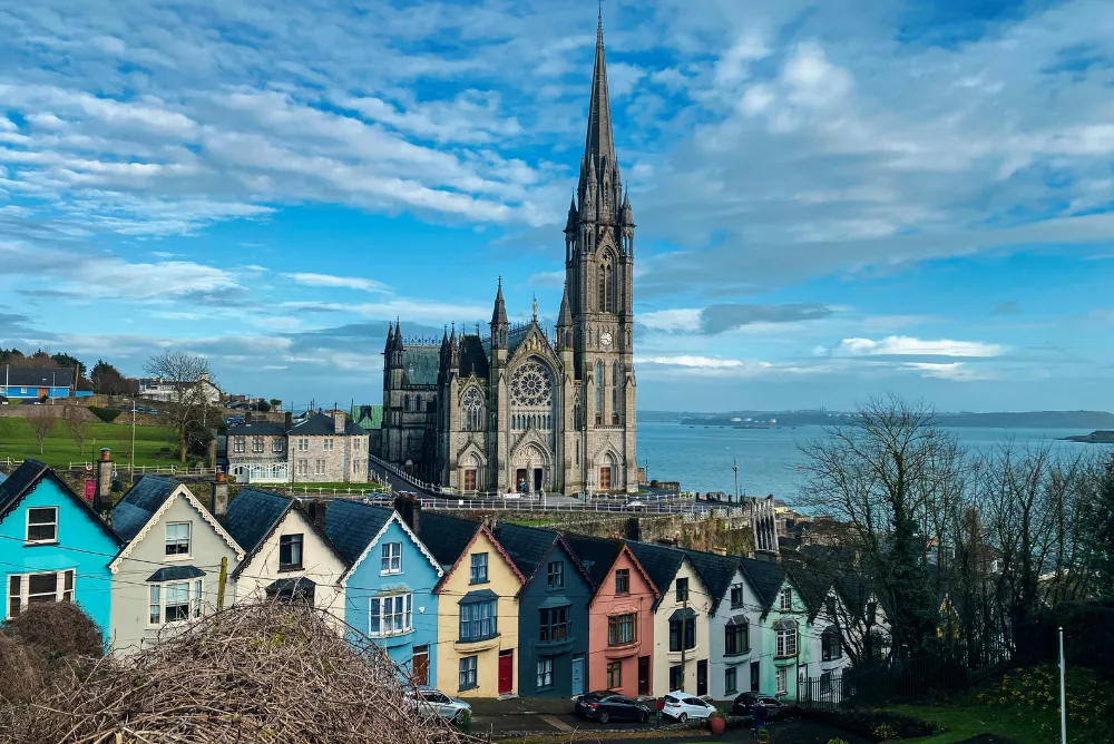 A row of brightly painted houses on the Cobh waterfront below St Colman's Cathedral